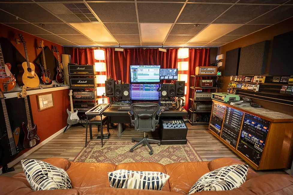Somni Studios control room with mixing console, monitors, guitars, and professional studio equipment