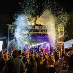 Festival crowd celebrating with confetti and lights at outdoor music event in Bend Oregon