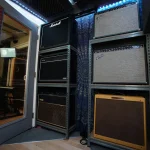 Wall of amplifiers including Marshall, Fender, and Vox units in Somni Studios.