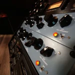 Blue analog equalizer and mastering rack glowing under warm studio lighting.