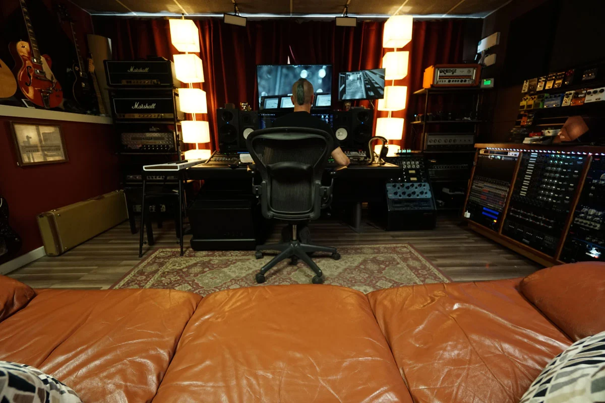 Audio engineer Matt Fletcher mixing in the Somni Studios control room, wide view from couch.