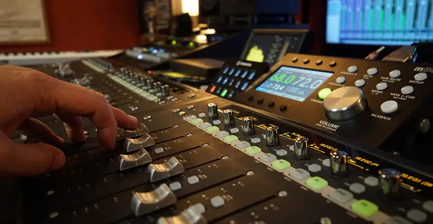 Audio engineer adjusting levels on a professional mixing console at Somni Studios in Bend, Oregon recording studio