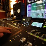 Audio engineer Scott Baber adjusting faders on the mixing console at Somni Studios.