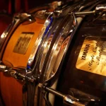 Yamaha Maple Custom Absolute snare drum with gold badge and natural wood finish at Somni Studios.